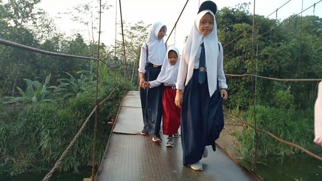 Siswa dari Kampung Dukuh, Desa Parungkujang, Kecamatan Cileles, Kabupaten Lebak melintasi jembatan usang.